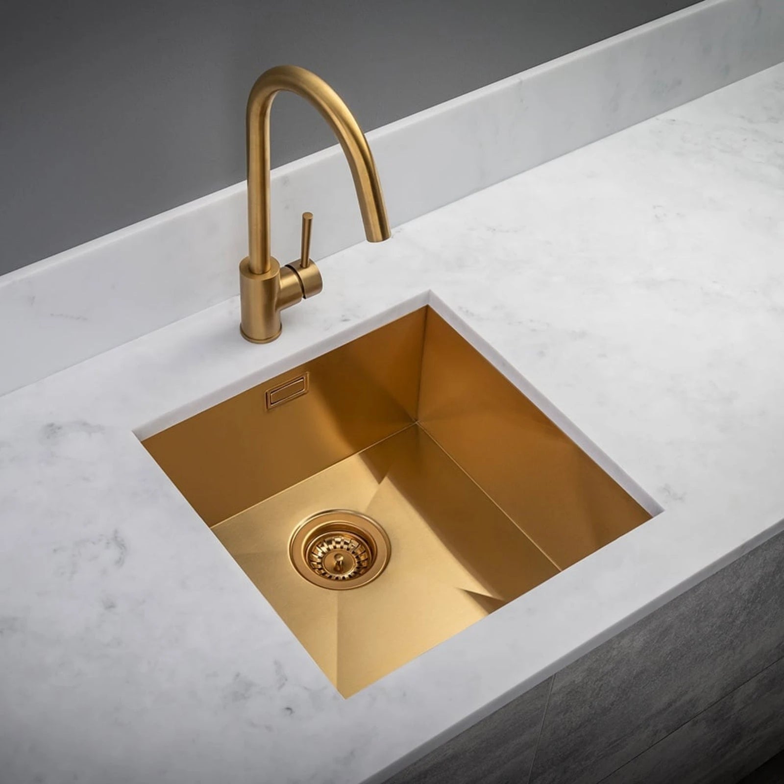 Gold kitchen sink with faucet on a marble countertop