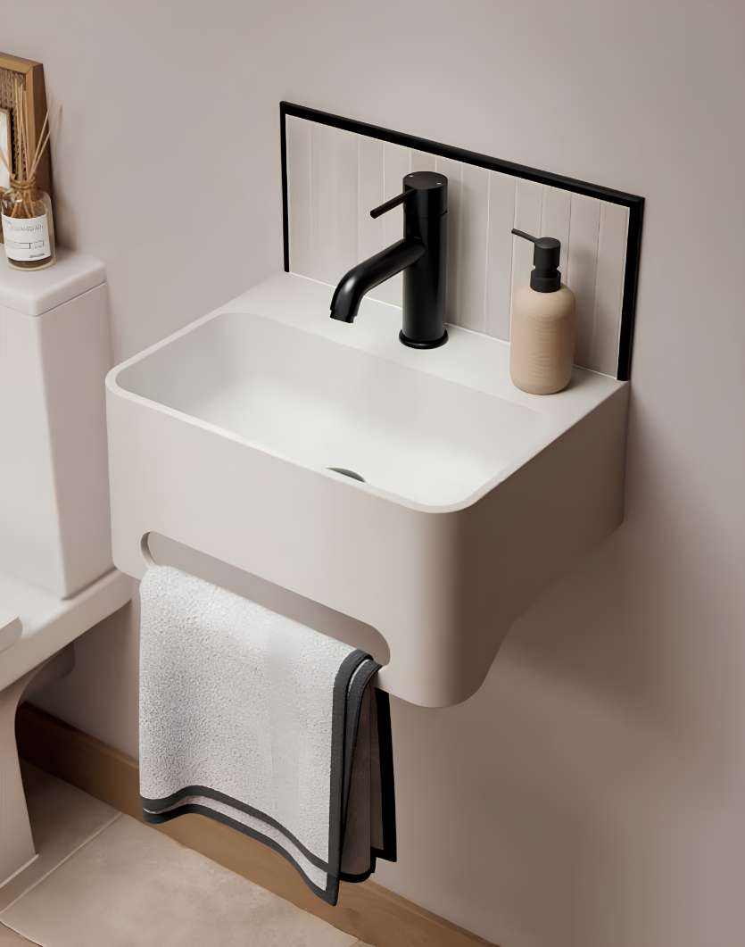 Modern bathroom sink with black faucet, soap dispenser, and towels.