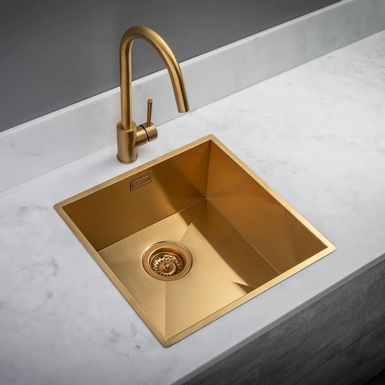 Gold kitchen sink with faucet on a white countertop