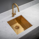 Gold kitchen sink with faucet on a marble countertop