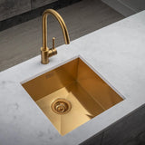 Gold kitchen sink with faucet on a marble countertop